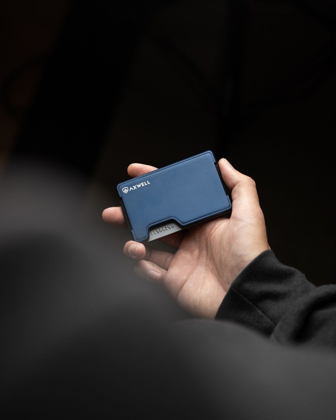 A slim blue card wallet held in one hand