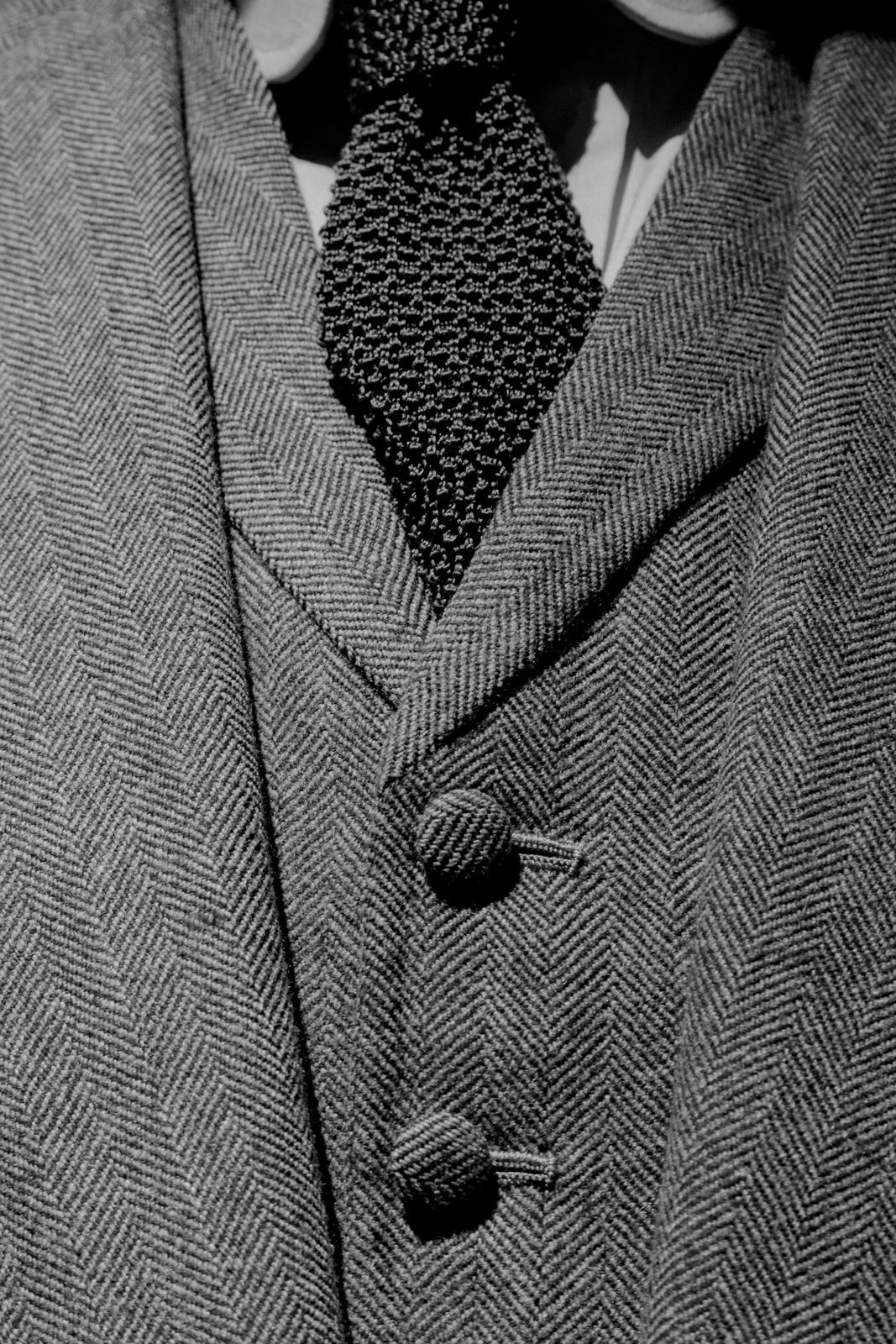 A knitted tie against a textured jacket