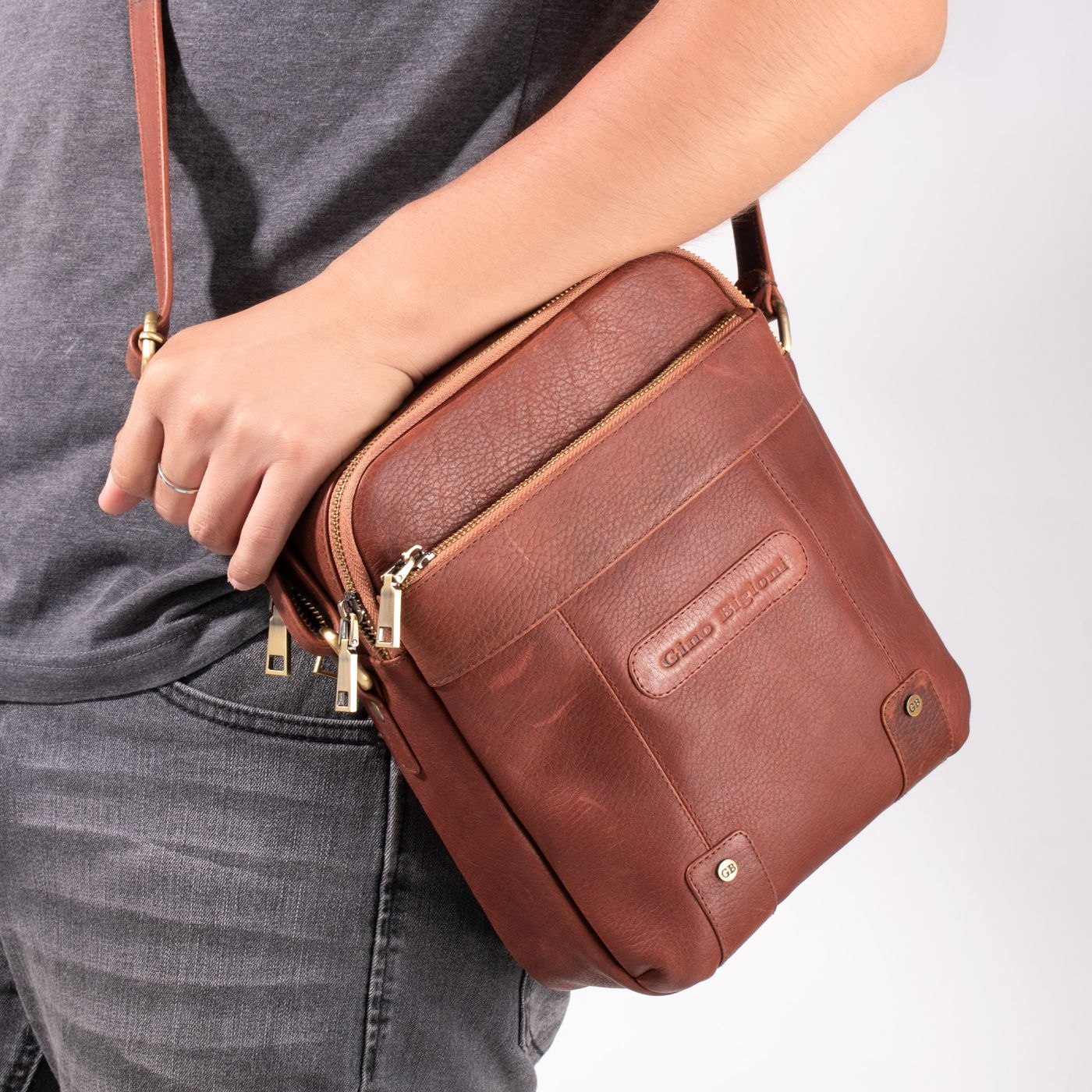 A compact brown leather shoulder bag with zipped compartments
