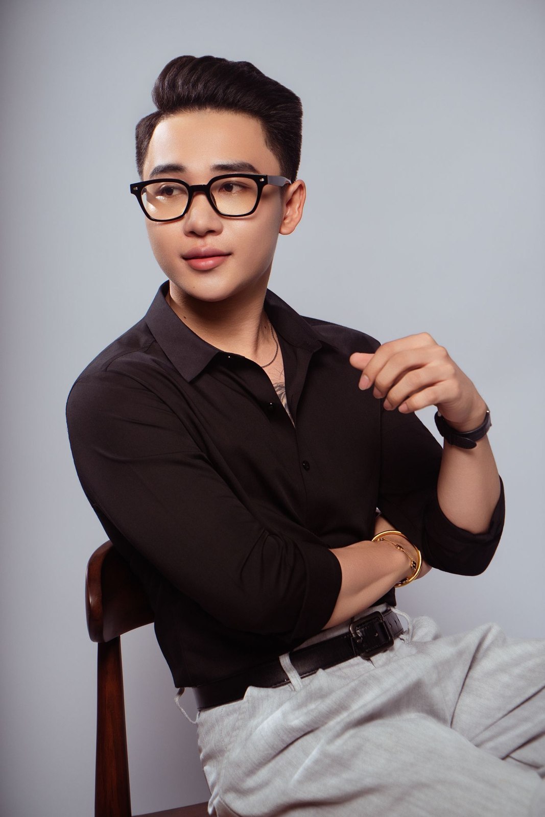 A dark shirt tucked into pale trousers
