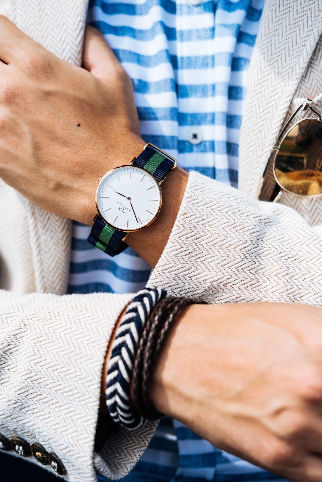 A watch and bracelets beside a checked shirt