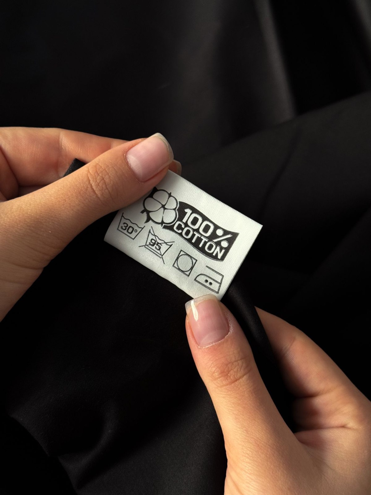 A clothing care and composition label held for inspection